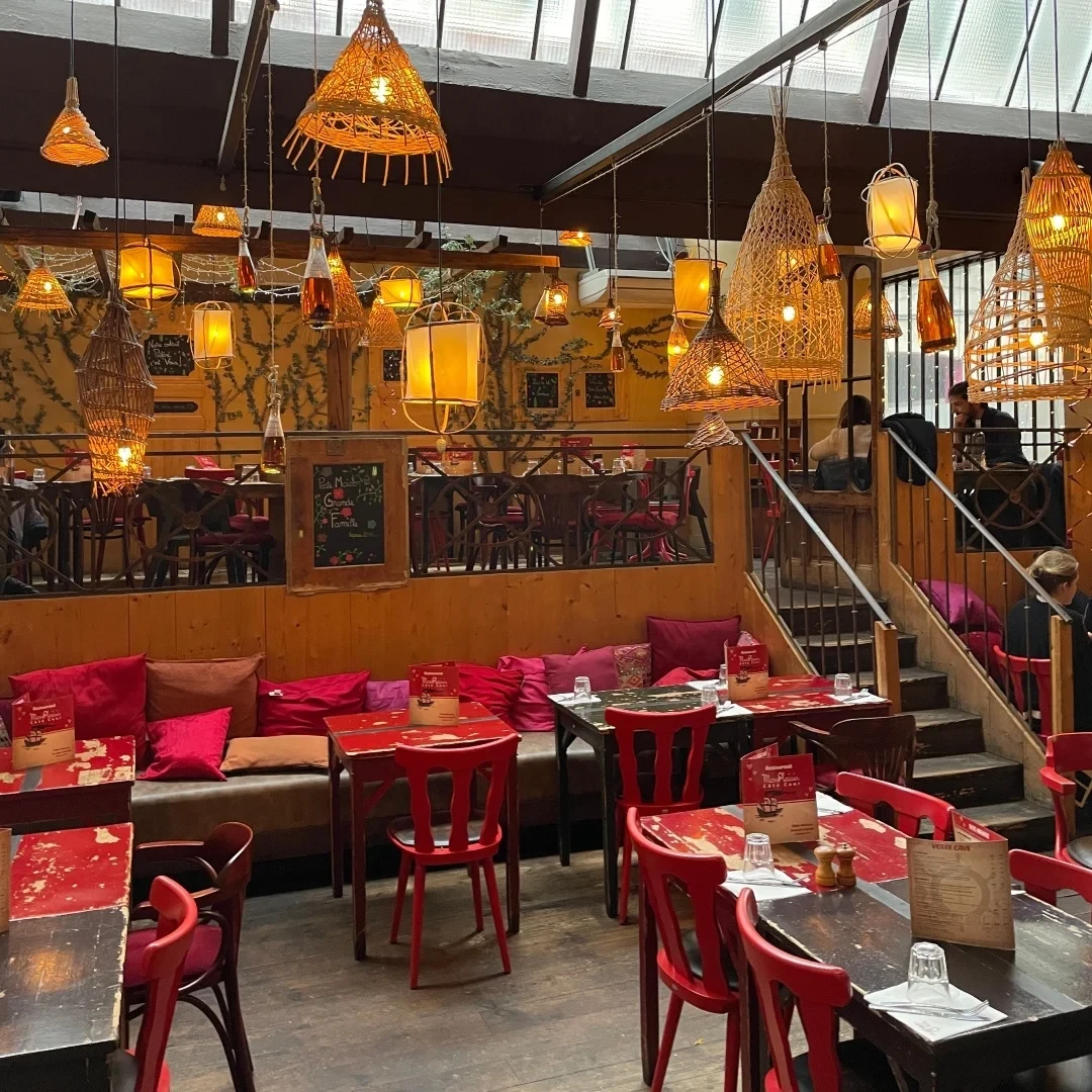 Intérieur cosy d'un café avec des lumières suspendues et des sièges rouges.